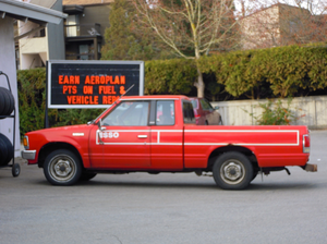 Old Red Nissan Pickup Truck At Gas Station Image