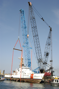 Two Cranes Work In Tandem From A Barge To Lower A U.s. Coast Guard (uscg) Patrol Boat Into The Water. Image