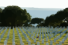 A Tugboat Tows The Decommissioned Aircraft Carrier Midway Past Fort Rosecrans National Cemetery To San Diego Bay. Clip Art